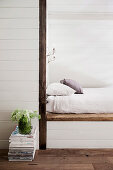 Built-in sleeping niche with mattress, in the foreground a stack of magazines and a bouquet of flowers