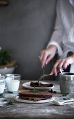 A woman cutting a chocolate pancake on a rustic wooden table