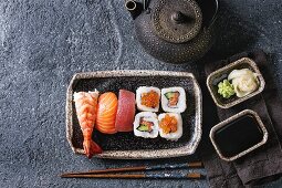 Nigiri-Sushi und Maki-Sushi auf Keramikplatte dazu Sojasauce, Wasabi und Ingwer