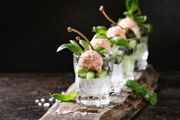 Verrines appetizer with salmon pate, red caviar, cucumber, cream cheese, herbs, capers in glasses served with pink salt and basil