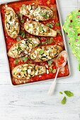 Aubergines stuffed with rice, zucchini and feta in tomato sauce on an oven tray