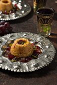 Honey semolina cakes with saffron, dark red grapes and green pistachios