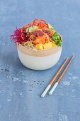 A Poke bowl with tuna, salmon, sushi rice, tobiko, avocado, carrots, mango, and sprouts