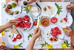 A summer breakfast table with cheese, melon, figs and coffee