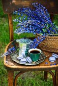 A cup of coffee, an espresso pot, and macarons on a silver tray, with lupines in a basket (outdoor garden)