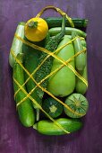 Various courgettes wrapped in netting with a handle