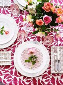 Romantisches Gedeck mit Glasteller und Rosenblüte