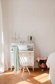 Scandinavian spoke-back chair at white bureau in bedroom