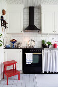 Red stool in Scandinavian country-house kitchen with classic cooker