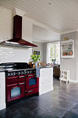 Red cooker in large, white country-house kitchen with grey floor