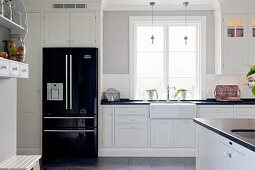Schwarzer Kühlschrank in weißer Landhausküche mit Kassettenfronten