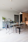 Various chairs around dining table in front of plywood kitchen