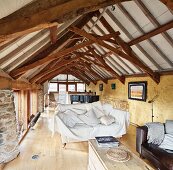 Grand piano in bright lounge area of rustic attic with restored roof structure