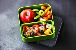 Take out food Greek salad and Apple fruit in Lunch box on blackboard background