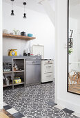Patterned floor and stainless steel cabinets in open-plan kitchen