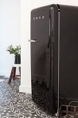 Black retro fridge on patterned floor tiles