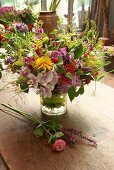 Bunter Sommerblumenstrauß in Glasvase auf Holztisch