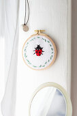 Fabric embroidered with ladybird in embroidery frame