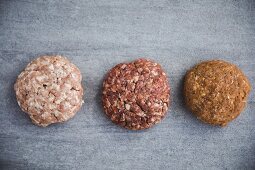 Three different raw organic pork burger patties (seen from above)