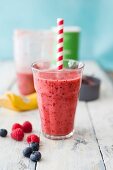 Grapefruit and berry smoothie with a straw in a glass