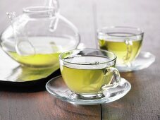 Green tea in a glass cup and a glass pot
