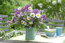 Early summer flowering perennials bouquet in a green pot