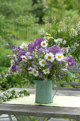 Early summer flowering perennials bouquet in a green pot