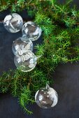 Glass Christmas-tree baubles and green conifer branches