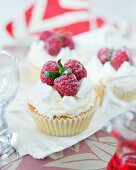 Cupcakes verziert mit Sahne, Baiserstückchen und Himbeeren