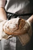 A baker holding a loaf of freshly baked bread