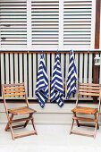 Hanging towels and two wooden folding chairs at the pool edge