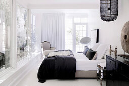 Doppelbett und Sessel in großzügigem Schlafzimmer mit Fensterfront