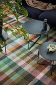 Two black coffee tables on tartan rug in living room