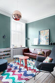 Petrol-blue walls and patterned rug in living room