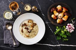 Risotto mit Steinpilzen auf Teller und dunklem Marmortisch (Aufsicht)