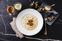 Risotto mit schwarzen Trüffeln auf Teller und dunklem Marmortisch (Aufsicht)