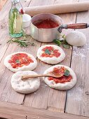 Unbaked pizzas with tomato sauce