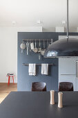 Black table in open-plan kitchen with hook rails mounted on grey wall