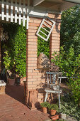 Backsteinpilaster mit Fenster und ländlicher Deko auf der Terrasse