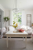 Leafy branch and basket of apples on coffee table in front of sofa