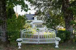 Gates of driveway leading to white Swedish house in woodland