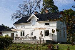 White Swedish house with black roof and terrace