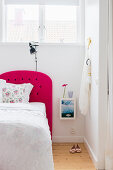 Double bed with hot-pink headboard in white bedroom