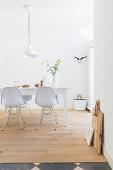 White dining area: dining table and classic chairs on wooden floorboards