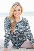 Junge blonde Frau in grau-weißem Strickpullover