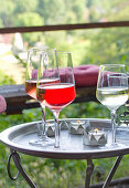 DIY-Sommerlichter aus Metalldosen und Weingläser auf Tabletttisch im Garten