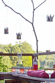 DIY-Sommerlichtern aus Metalldosen über Gartenbank auf Naturterrasse