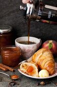 Frühstück mit Kaffee, Croissant, Pfirsichmarmelade und Butter