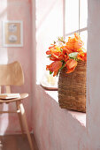 Basket of orange parrot tulips on windowsill