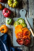 Different-coloured heirloom tomatoes in slices on a chopping board